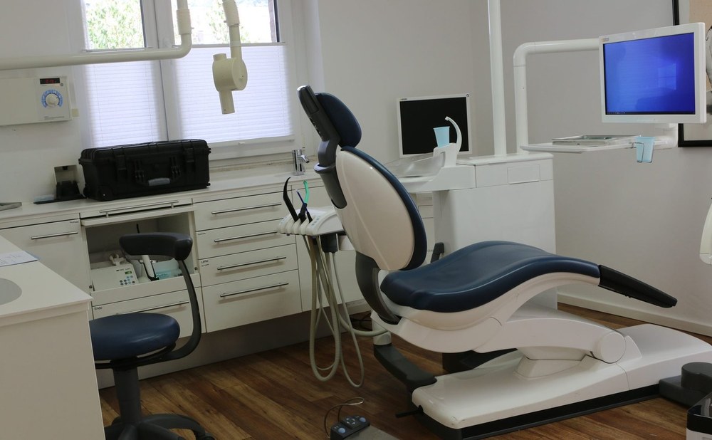 Helles Behandlungszimmer mit Behandlungsstuhl und Monitor